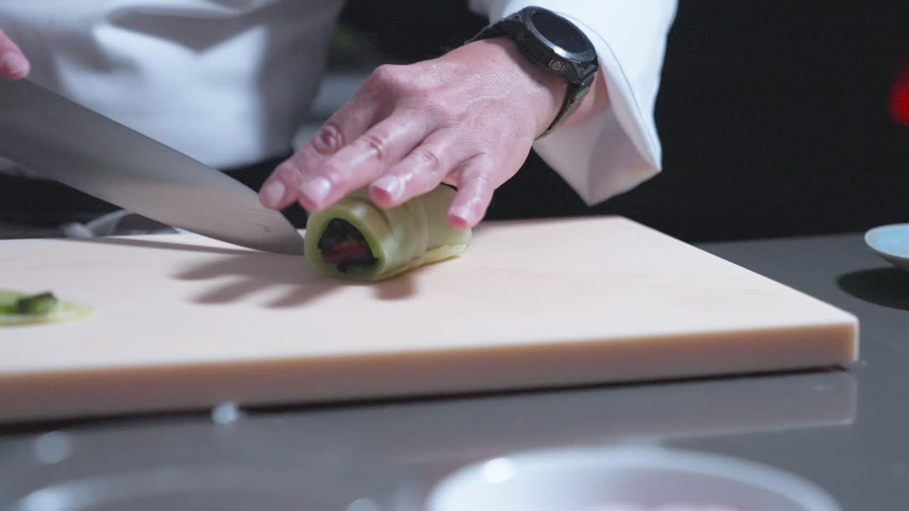 A sushi chef carefully slices fresh cucumber rolls into perfect pieces. Ideal for showcasing sushi preparation, Japanese cuisine, culinary skills, and professional food presentation.
