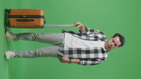 full body of asian male traveler with luggage and passport having a headache while standing in the green screen background studio