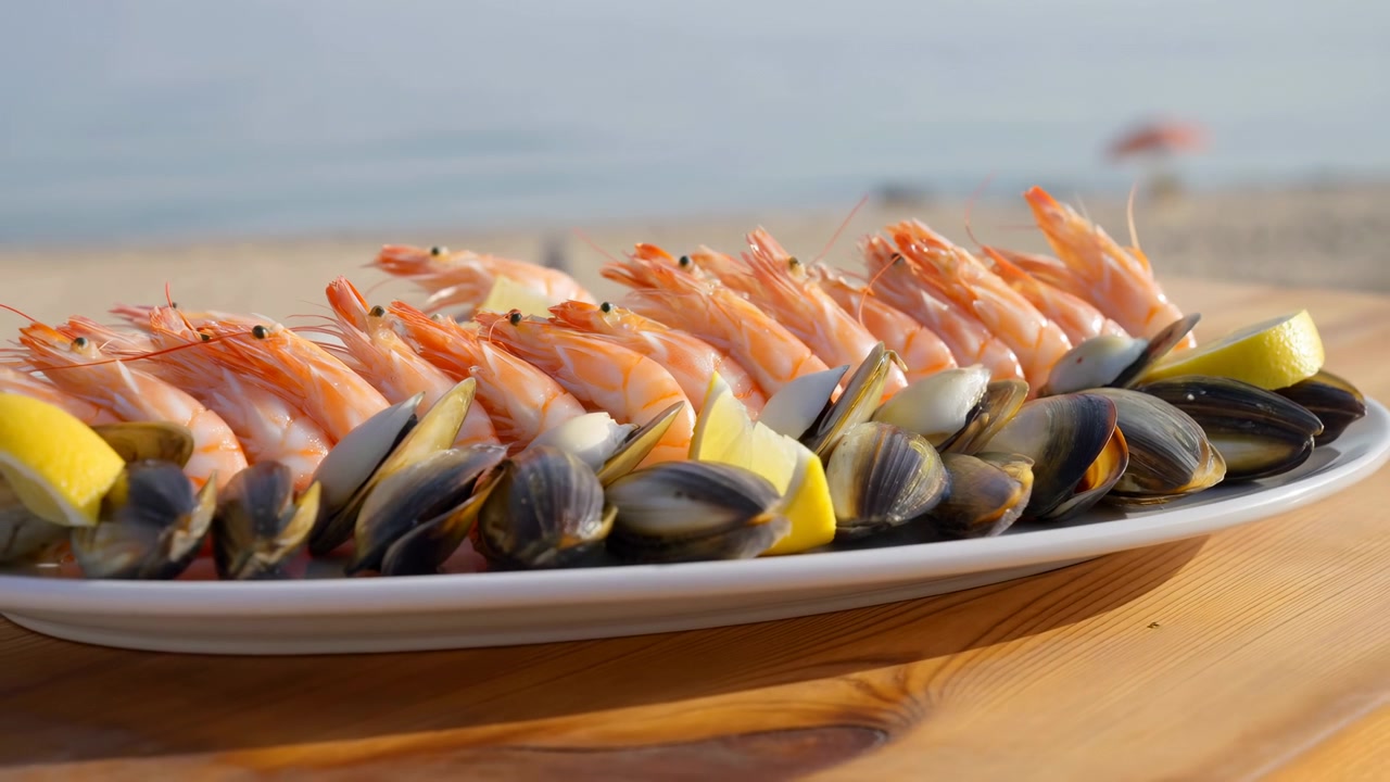 Seafood Platter With Shrimp And Mussels, Lemon Wedges On Wooden Table By Beach, Sunlit Summer Scene