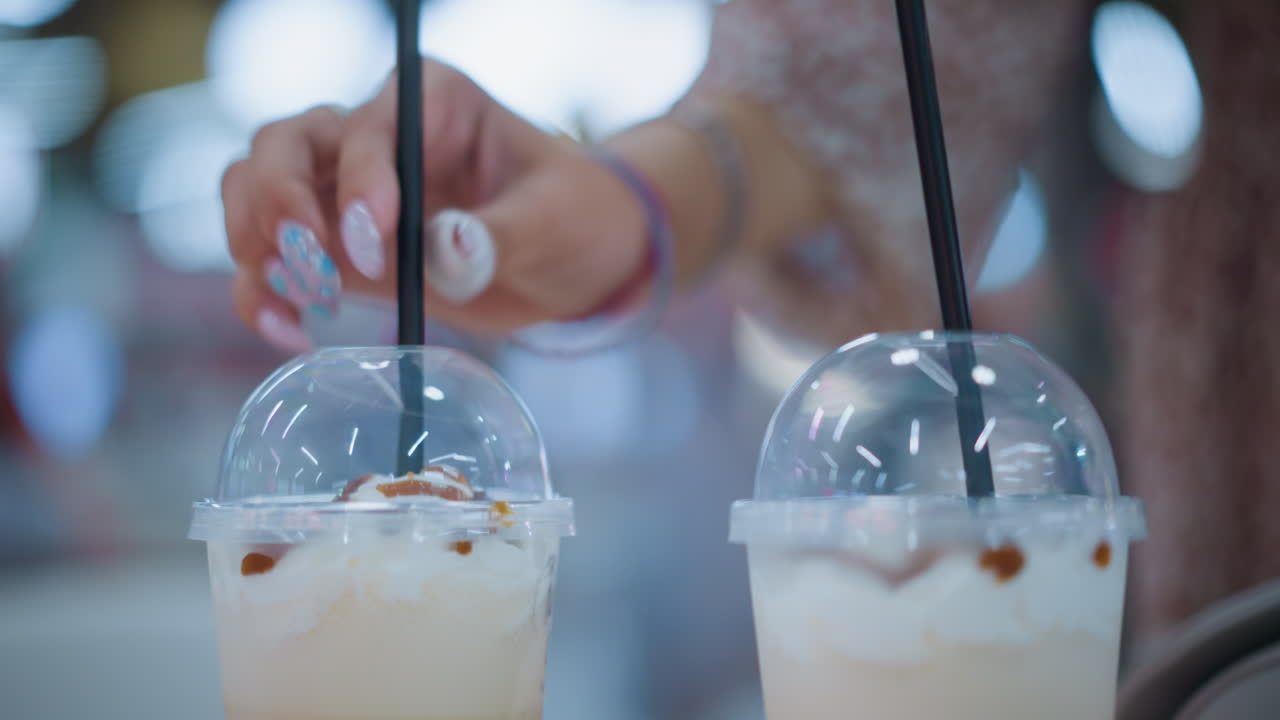 테이블 위에 두 개의 크림 음료가 검은 을 입하는 사람과 함께, 부드러운 보케 조명과 레스토랑에서 사람들의 움직임을 보여주는 흐릿한 배경으로 캐주얼 식사 분위기를 만니다.