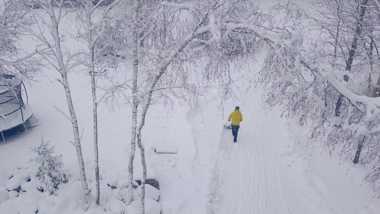 Aerial bird's eye view of man shoveling heavy snow, winter white landscape