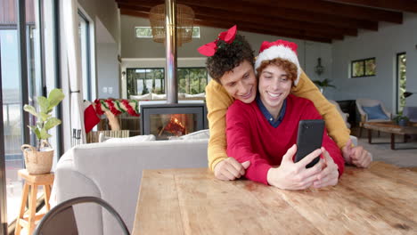 pareja de hombres homosexuales diversos usando el teléfono inteligente para llamadas de video en casa, cámara lenta, espacio de copia