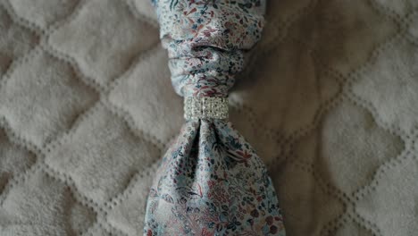 close up of a floral tie with a jeweled tie pin, highlighting intricate wedding accessories