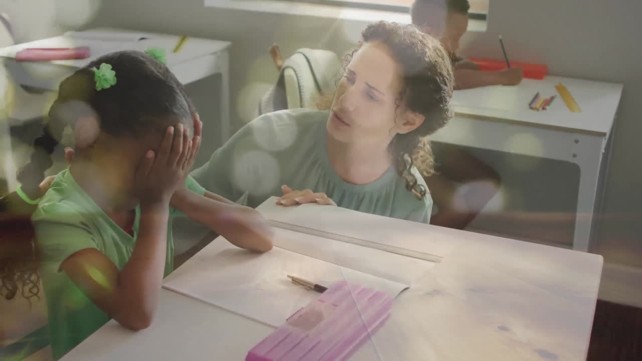 Animazione di luci bokeh su un'insegnante donna di diverse etnie che parla con una scolaretta triste al banco in classe