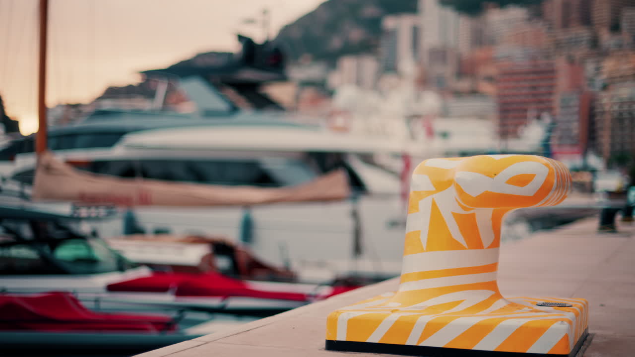Close up of a white and yellow dock cleat in a harbour with boats on the background