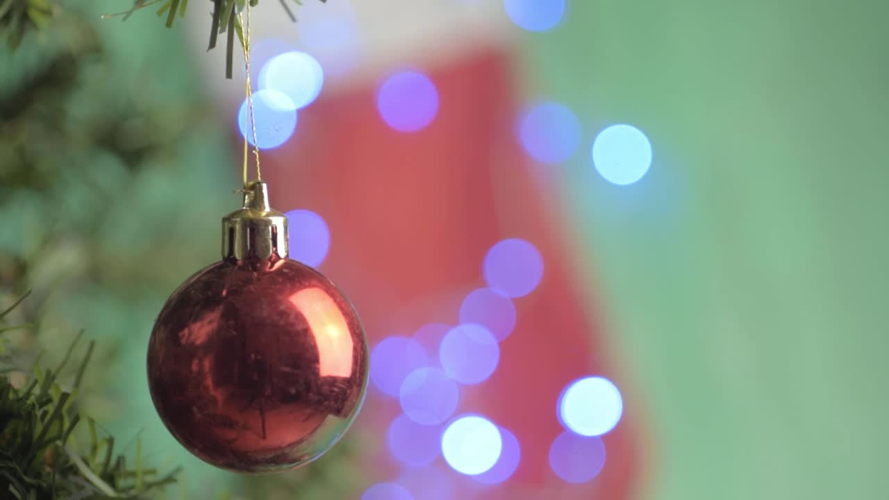 adornos navideños rojos con luces bokeh colgando del árbol con fondo navideño