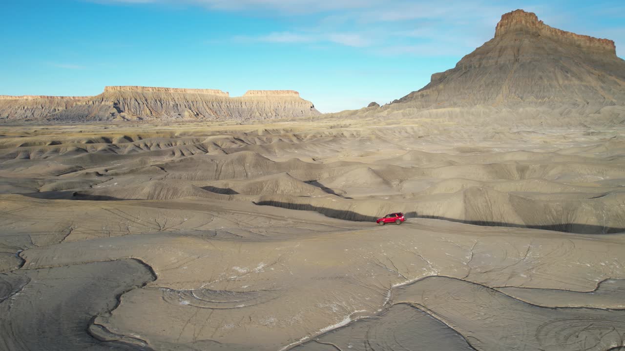 vista aérea de un suv rojo en el paisaje desértico cerca de factory butte, vehículo de conducción en un camino de tierra, disparo de dron