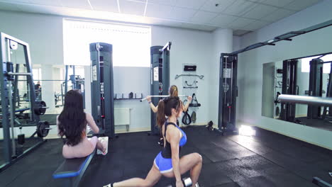 strong woman bodybuilders doing workout in a modern gym. muscular girls in sportswear exercising heavily. camera moves back.