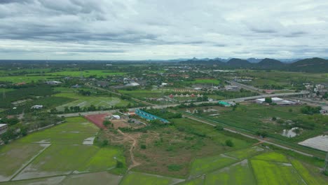 aerial drone over the plains of ratchaburi province in thailand with green paddy fields and roads