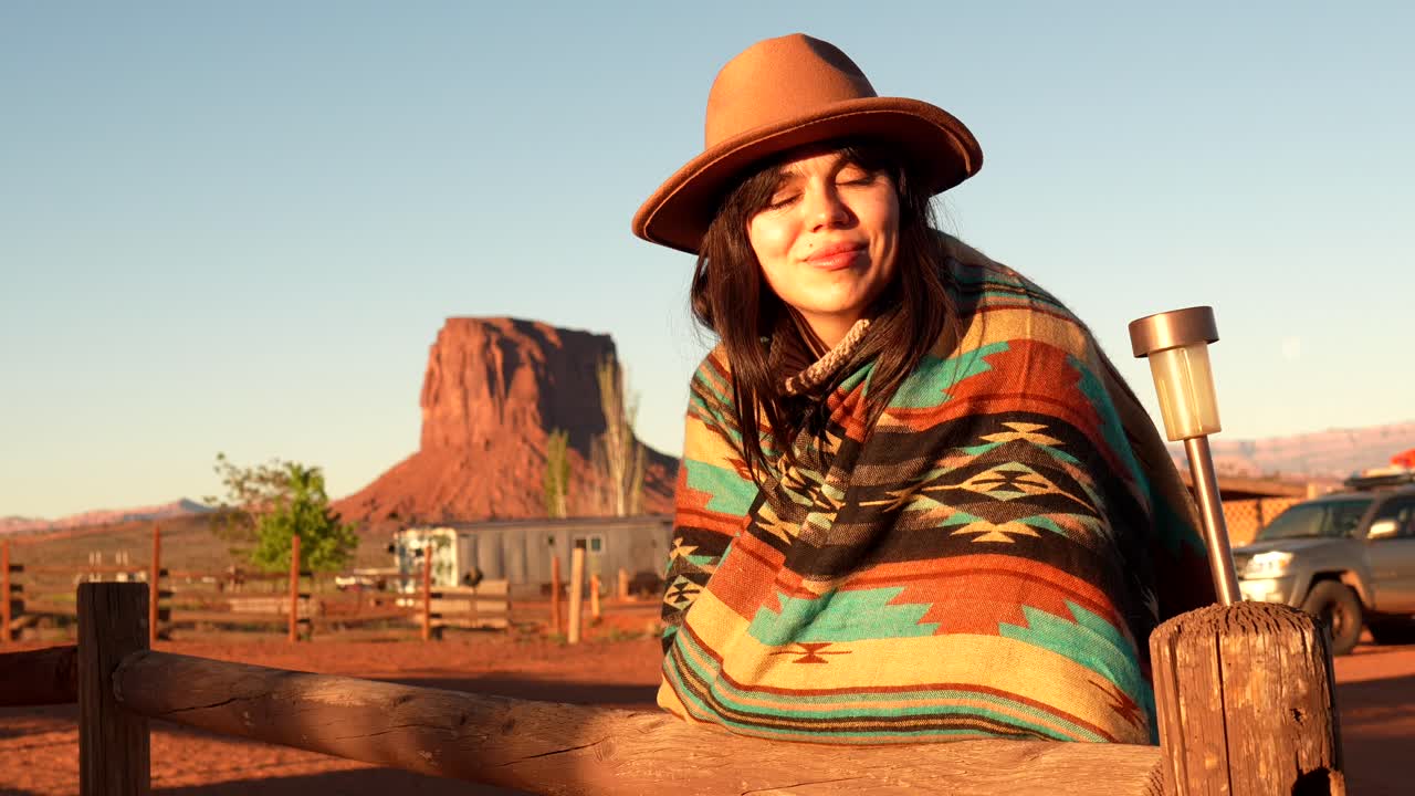Donna felice con cappello e poncho che si gode il tramonto nel deserto