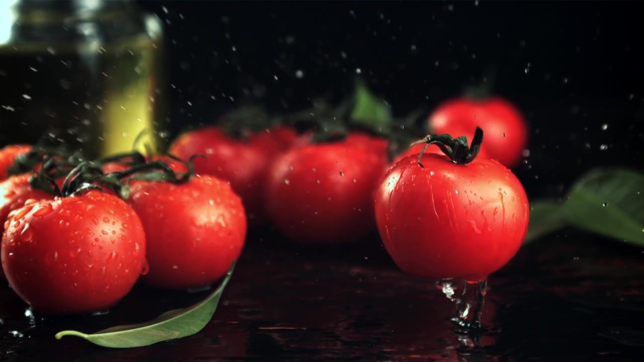 Frische rote Kirschtomate, die in Zeitlupe fällt und Wasser spritzt