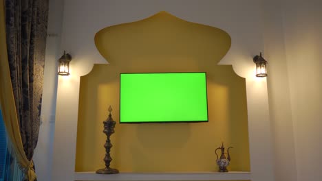 pared con televisión y pantalla verde al estilo de oriente medio y áfrica del norte. mano con control remoto. copa árabe en qatar