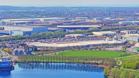 high-angle aerial view of the doncaster lakeside shopping area in south yorkshire, england, with retail buildings, packed parking lots, landscaped green spaces, and lake edge clearly visible