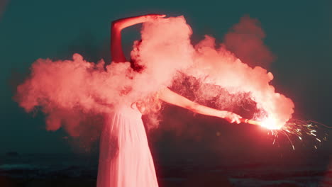 Mujer-Agitando-Bengalas-Bailando-En-La-Playa-Al-Amanecer-Quemando-Fuegos-Artificiales-De-Señales-De-Socorro