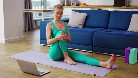 Woman-in-sportswear-talk-on-video-call,-explain-pose-while-sits-on-a-mat