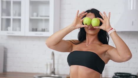 woman in kitchen ready to prepare meal with vegetables and fruits. woman is holding apples near her eyes. kitchen background. healthy food. vegans and vegetarians