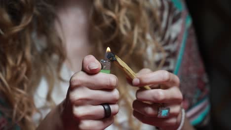 hippie girl burning piece of wood with lighter, basic elements of life