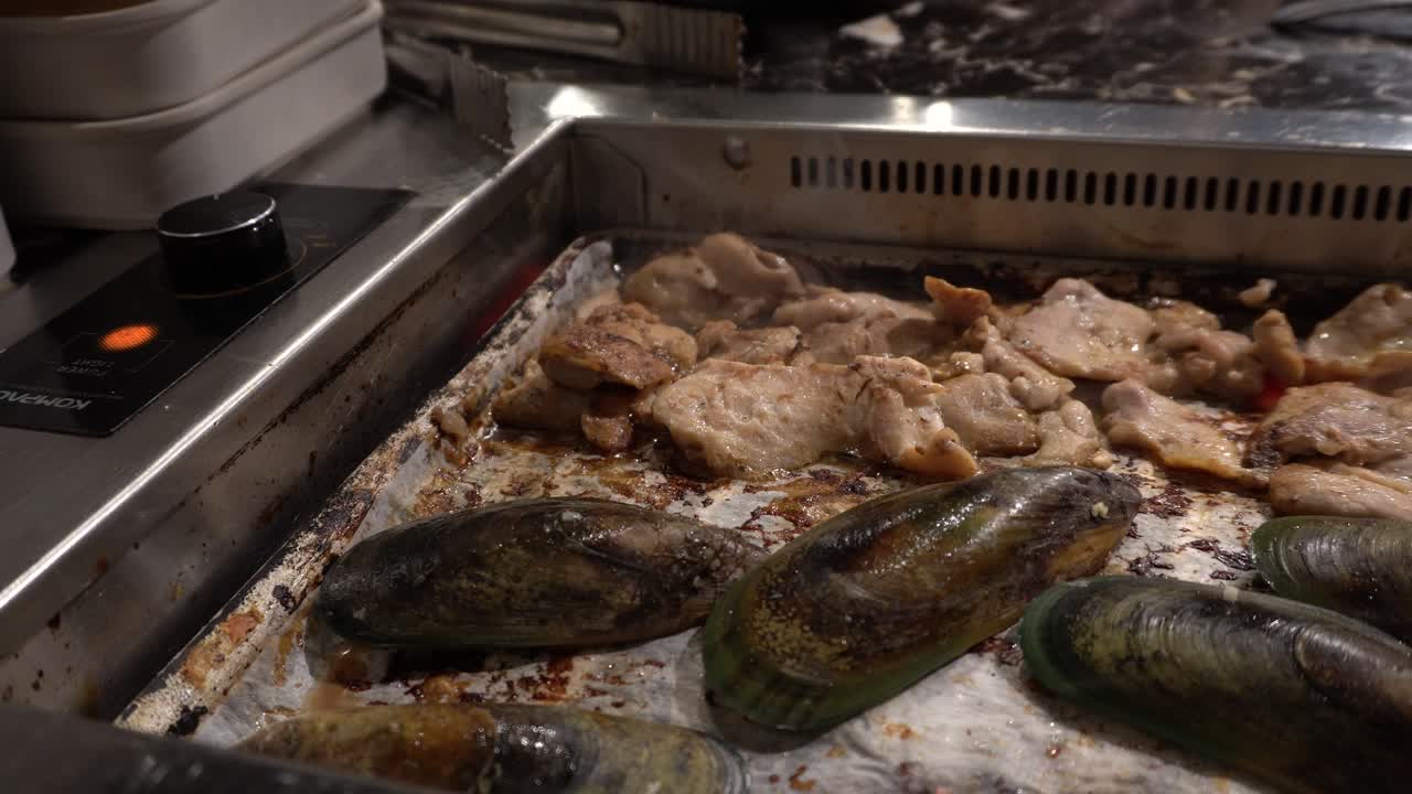A close-up view of someone preparing the meat on a Korean BBQ restaurant