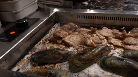 una vista de cerca de alguien preparando la carne en un restaurante coreano de bbq