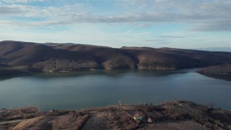 Panoramic-aerial-shot-of-the-lake-Cincis-in-Romania,-surrounded-by-the-mountains