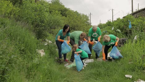 Team-of-nature-activists-in-eco-T-shirts-picking-up-plastic-trash-in-park.-Recycle,-earth-pollution