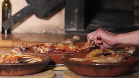 Suckling-lamb-quarters-recently-baked-in-an-ancient-clay-wood-oven,-at-the-background-of-the-image