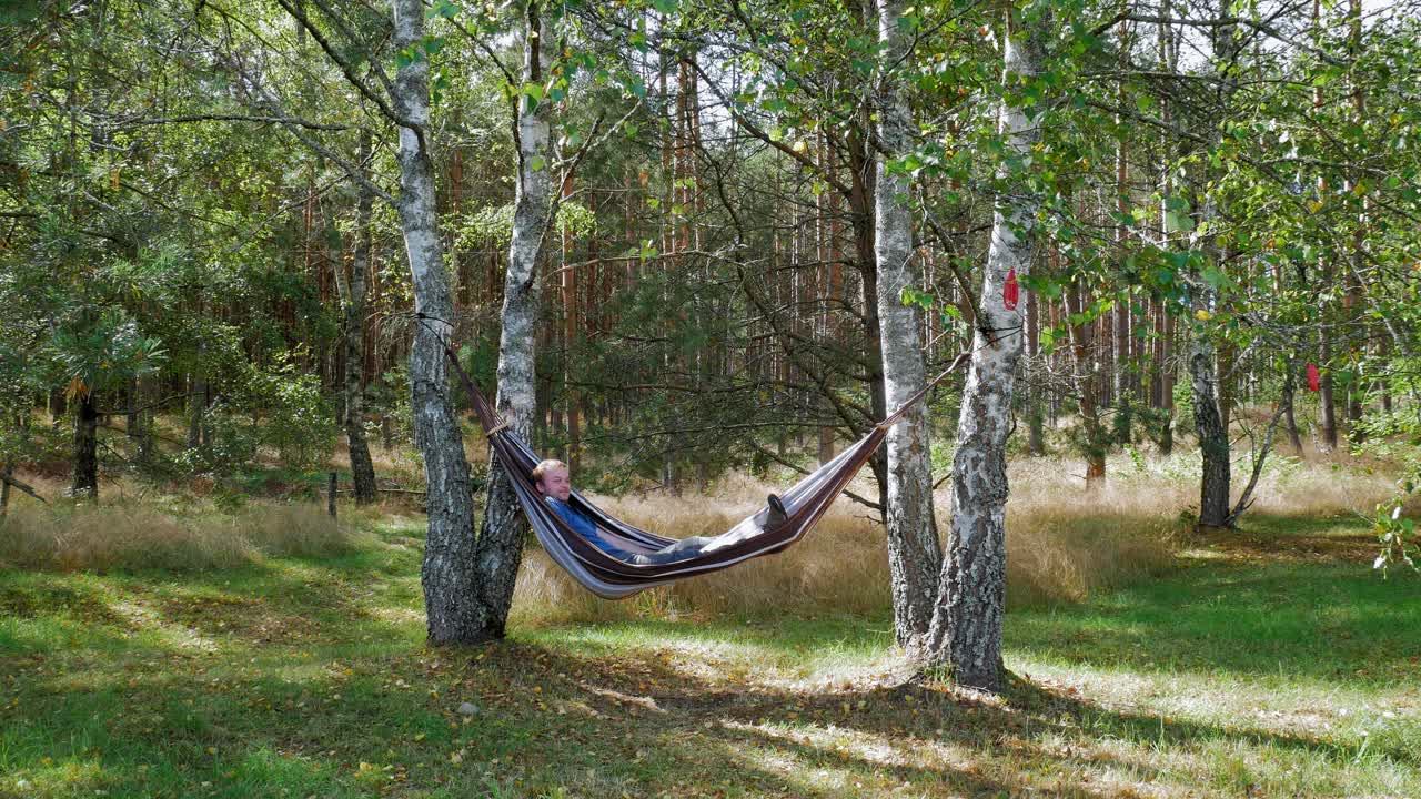 hombre columpiándose en una hamaca disfrutando de la belleza de la naturaleza durante el día soleado en el bosque de pradzonka, al norte de polonia