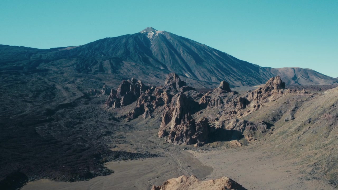 La vetta vulcanica del Monte Teide che si erge sopra le frastagliate formazioni rocciose dei Roques de García nel Parco Nazionale del Teide, a Tenerife, in Spagna, contro un cielo azzurro limpido