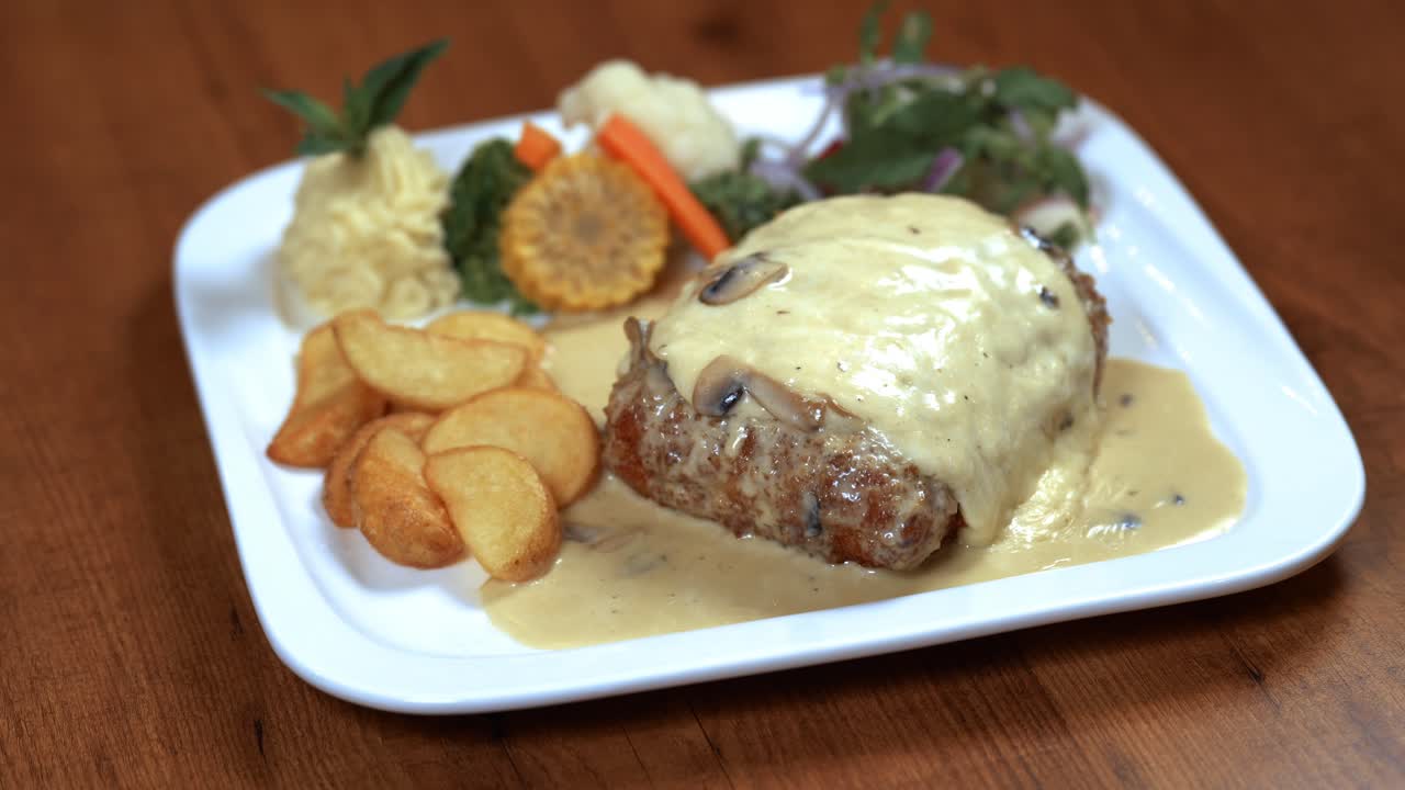 cordon bleu con harina de queso sobre una mesa de madera con arroz y patatas - vista superior 4k