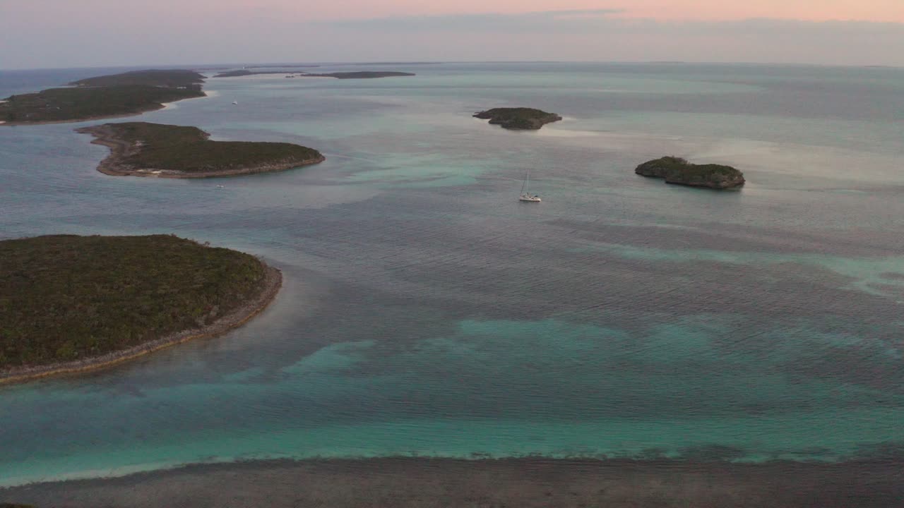 vista aérea de drones de un velero solitario en el mar caribe entre pequeñas islas al atardecer