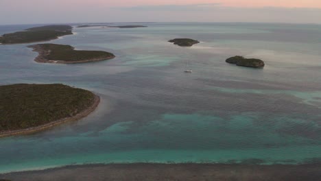 drone aerial view of lonely sailing boat in caribbean sea between small islands at twilight