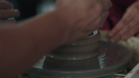 hands shaping clay on pottery wheel