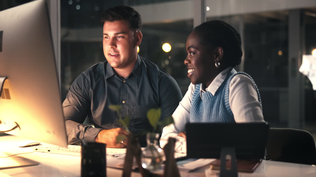 Colleghi diversi che collaborano al computer in un ufficio moderno di notte
