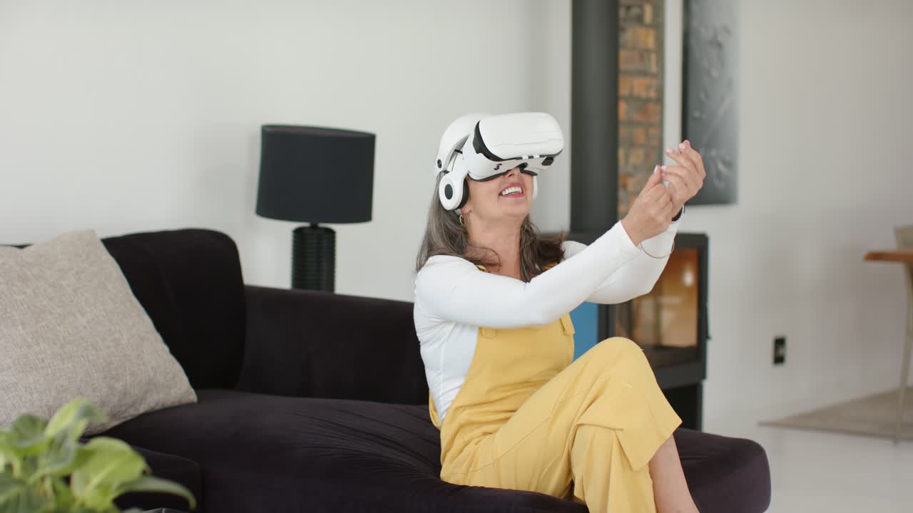 Sitting on black sofa in living room donning VR headset, woman is manipulating virtual interface