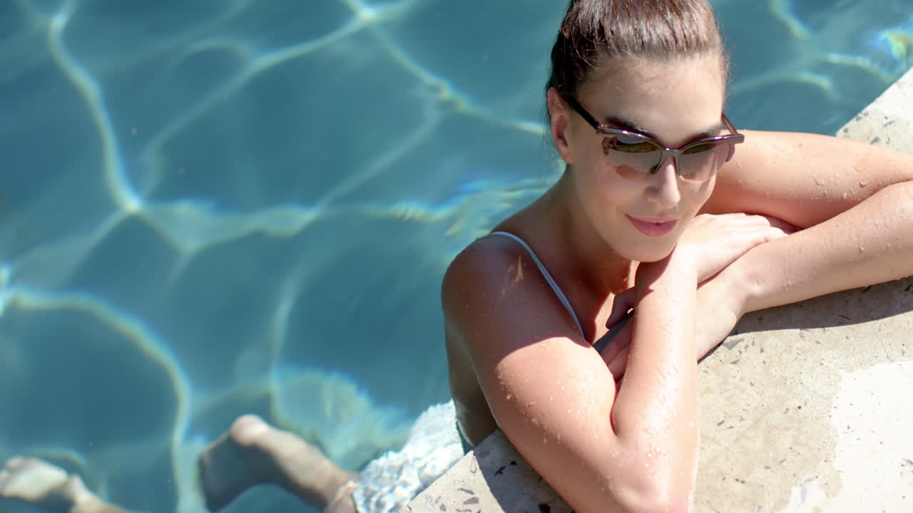 A young Caucasian woman relaxing in swimming pool, copy space