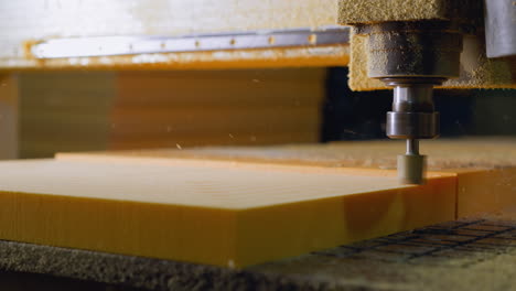 cnc milling machine cutting through yellow foam, detailed shot with particles