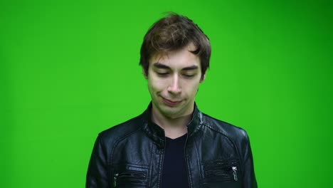 blanke man in leren jas knikt met zijn hoofd en zegt ja op groene achtergrond.