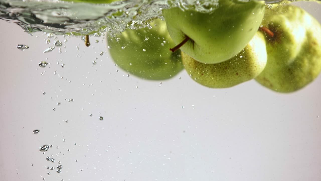 peras verdes y manzanas en salpicaduras de agua