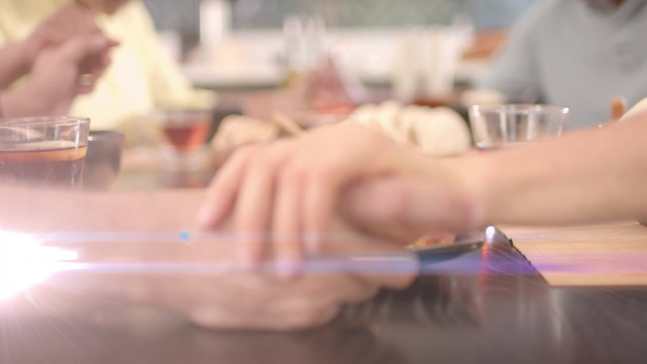 Family reaching table sharing food, hands clasping while animated flares accenting hands and buns