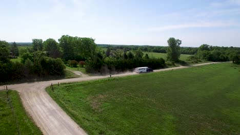 Aerial-large-horse-trailer-pulled-by-black-pickup-rumbles-down-a-rural-dirt-road-off-into-the-distance,-Kansas,-Missouri-Concept:-adventure,-the-road-less-traveled,-rural