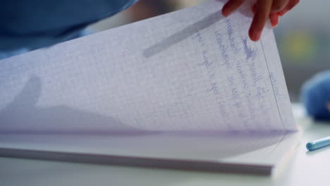 escuela mano haciendo trabajo de clase en el escritorio. niña escribiendo en el cuaderno