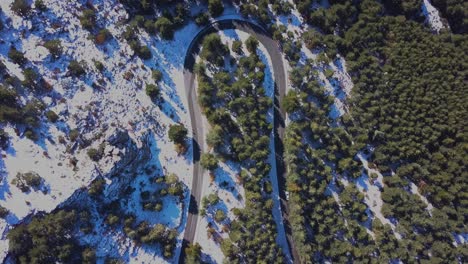 aerial view of a cruved road in a snowed moutain