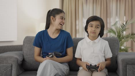 chica india molestando a su hermano después de ganar un videojuego