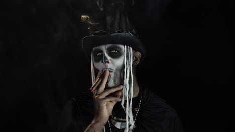 hombre siniestro con horrible maquillaje de halloween esqueleto fumando cigarro, haciendo caras, mirando a la cámara