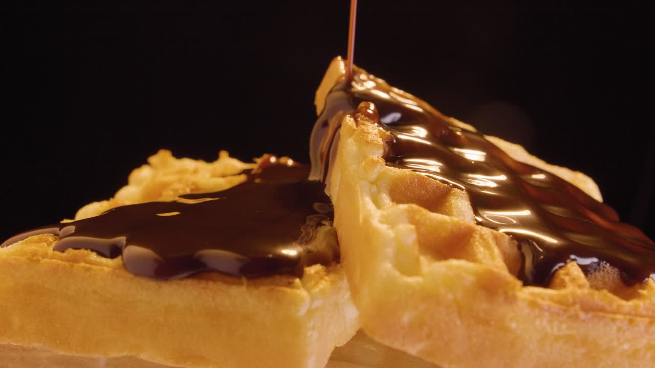 채식주의자 또는 채식주의자 초콜릿이 검은 배경에 쏟아지는 채식주의자 와플과 함께 맛있는 아침 식사를 마감합니다.