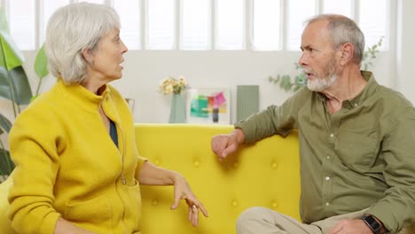 senior couple arguing on a yellow couch