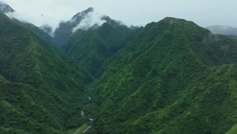 Tahiti-French-Polynesia-Teahupoo-aerial-drone-raining-fog-up-the-mountain-peaks-river-morning-grey-gray-season-wet-green-Point-Faremahora-village-town-South-Pacific-Mount-Tohivea-island-backwards-pan