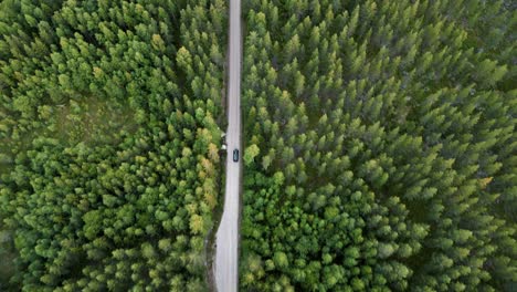 vista aérea de un vehículo aislado que corre en una carretera de campo boscosa en dalarna, suecia