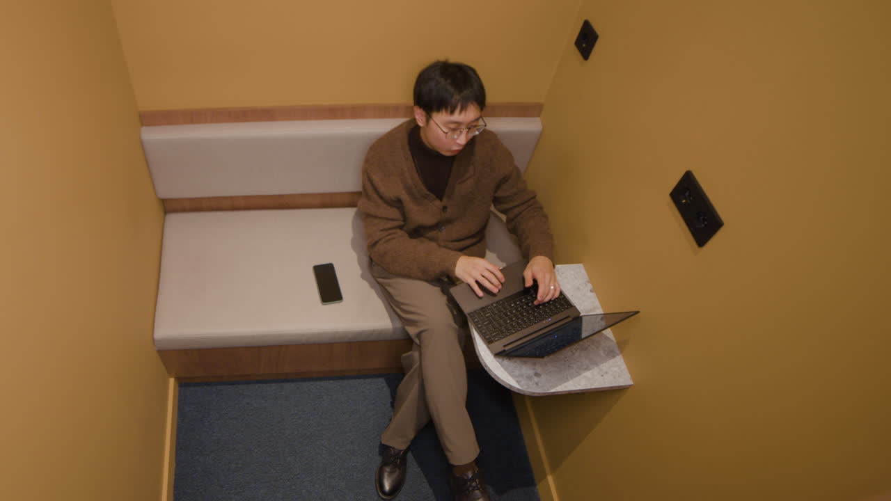 Man working on laptop in a booth