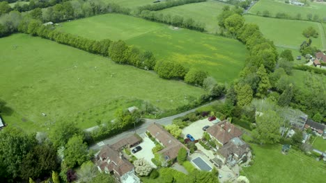 Aerial-view-tilt-down-over-idyllic-countryside-farm-property-patchwork-meadow-landscape